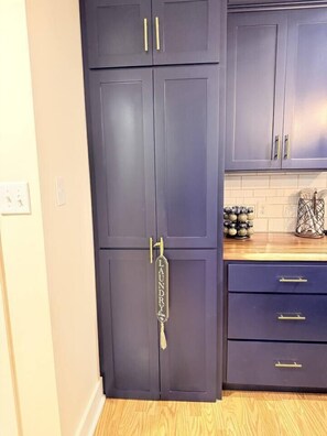 A kitchen with dark cabinets, a wooden countertop, and a hanging towel rack.