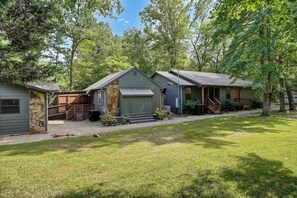 A row of cabins with a stone foundation, wooden decks, and a grassy yard.