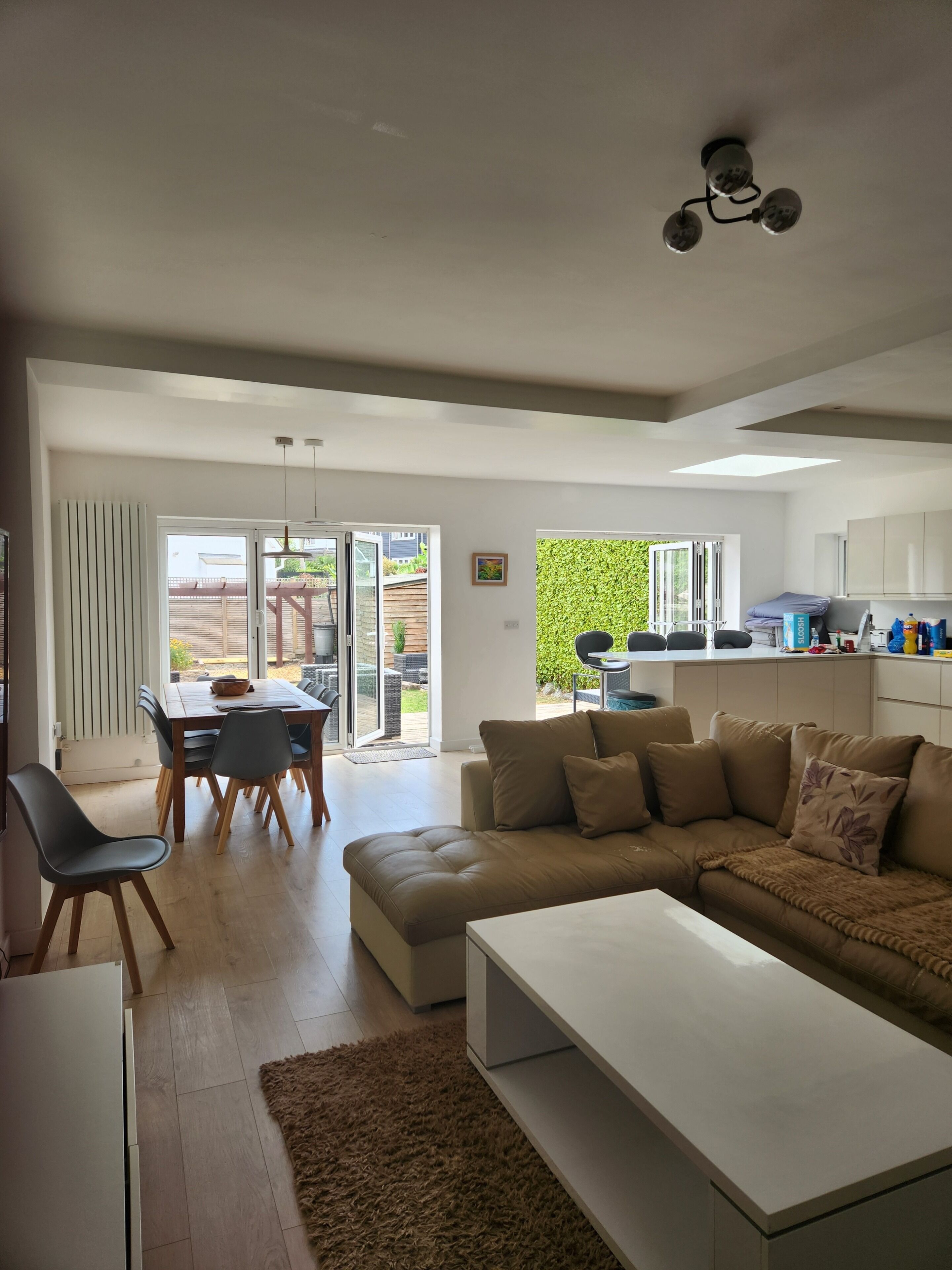 Una sala moderna con un sofá seccional, un comedor con mesa y sillas, y una cocina con armarios y encimera.