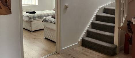 A staircase leading to a bedroom with a bed and a window.