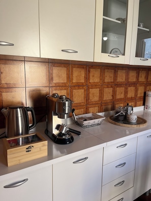 A kitchen with a coffee maker, a kettle, and a tray with jars.