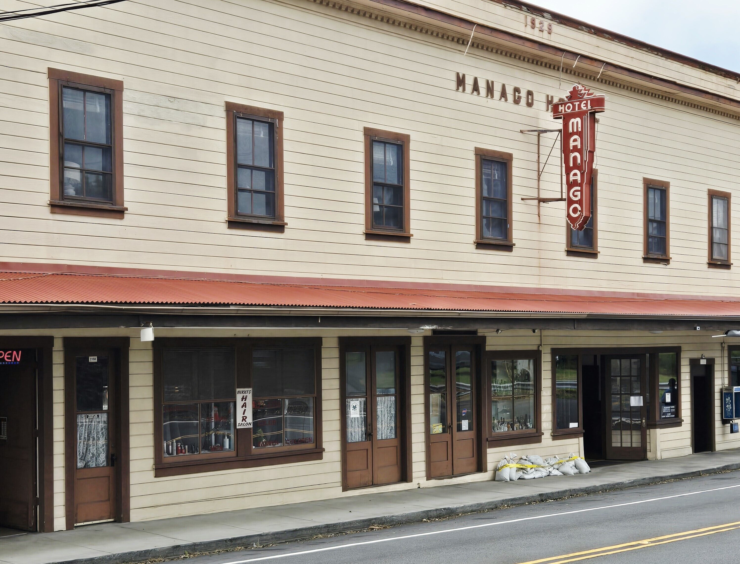 A two-story building with a sign reading 'MANACO HOTEL' and a 'NIKKI'S HAIR SALON' on the ground floor.