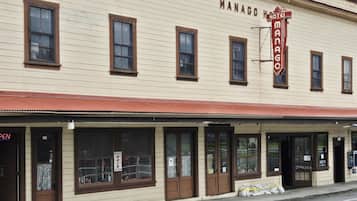 A two-story building with a sign reading 'MANACO HOTEL' and a 'NIKKI'S HAIR SALON' on the ground floor.