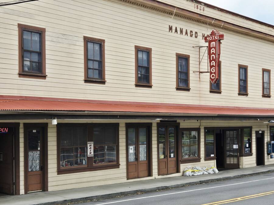 A two-story building with a sign reading 'MANACO HOTEL' and a 'NIKKI'S HAIR SALON' on the ground floor.