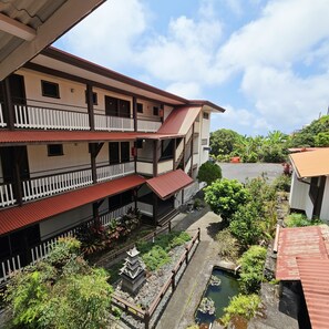 A multi-story building with balconies, a courtyard with a water feature, and surrounding greenery.