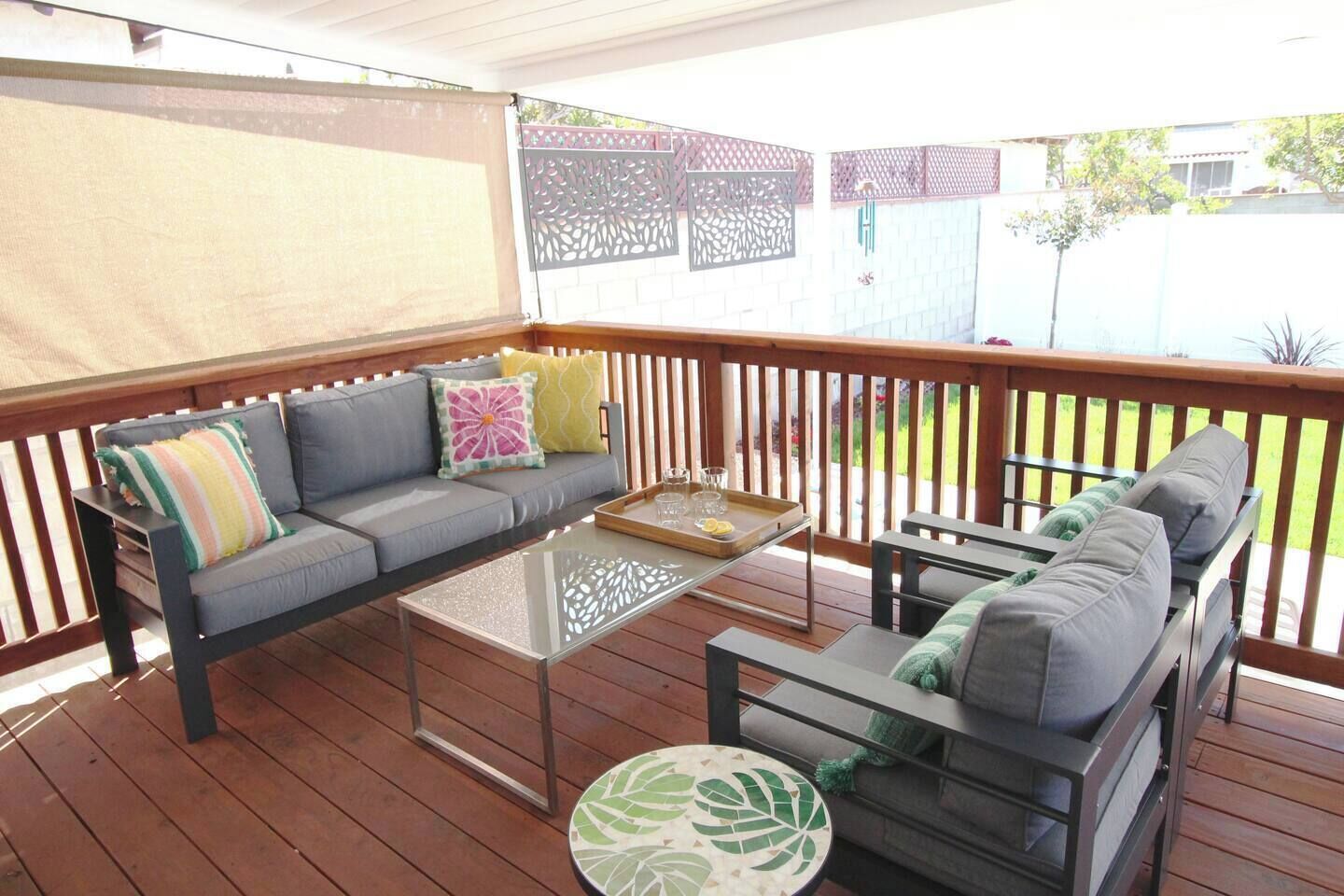 A covered outdoor seating area with a sofa, two side tables, and a small round table.