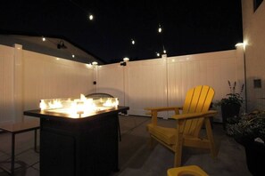 Eine Terrassengruppe mit Grill, Stuhl und Lichterkette.