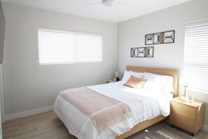 Quarto com cama, mesas de cabeceira e quadros na parede.