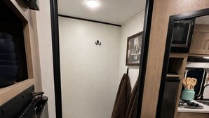 A compact bathroom with a toilet, a towel rack, and a small sink area. - Cozy Family Camper with Bunks (Fayetteville)