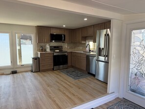 A modern kitchen with stainless steel appliances, wooden cabinets, and a large window. - Relaxing Getaway at Blue Cypress Lake (Vero Beach)