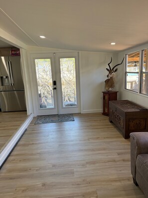 A modern interior with a wooden floor, a glass door with a floral pattern, a mounted antler head sculpture, and a wooden chest of drawers. - Relaxing Getaway at Blue Cypress Lake (Vero Beach)
