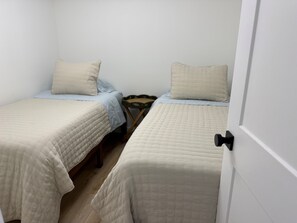 A small, compact room with two single beds, each with a pillow and a quilted bedspread. There is a small wooden chair and a radiator between the beds. - Relaxing Getaway at Blue Cypress Lake (Vero Beach)