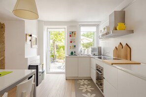 A modern kitchen with white cabinetry, a wooden countertop, and a view to the outside. - The hidden garden... with a sauna! (Torri del Benaco)