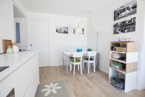 A compact kitchen with a dining area, a white cabinet with storage, a small table with chairs, and a shelf with kitchen items. - The hidden garden... with a sauna! (Torri del Benaco)