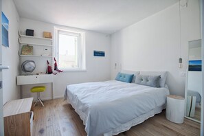 Ein Schlafzimmer mit Bett, Schreibtisch, Stuhl, Fenster und Spiegel.