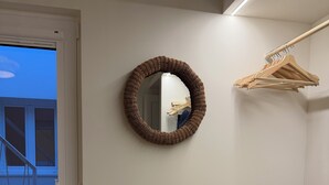 Una habitación con un espejo redondo, una silla de madera y un perchero.