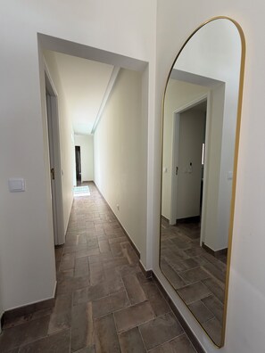 Ein Flur mit einem großen Spiegel und Fliesenboden.