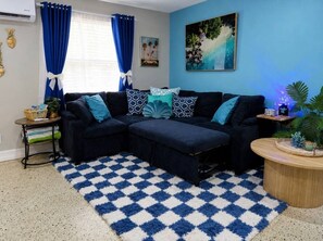 Ein Wohnzimmer mit einem Ecksofa, einem gemusterten Teppich und einem Bild an der Wand.