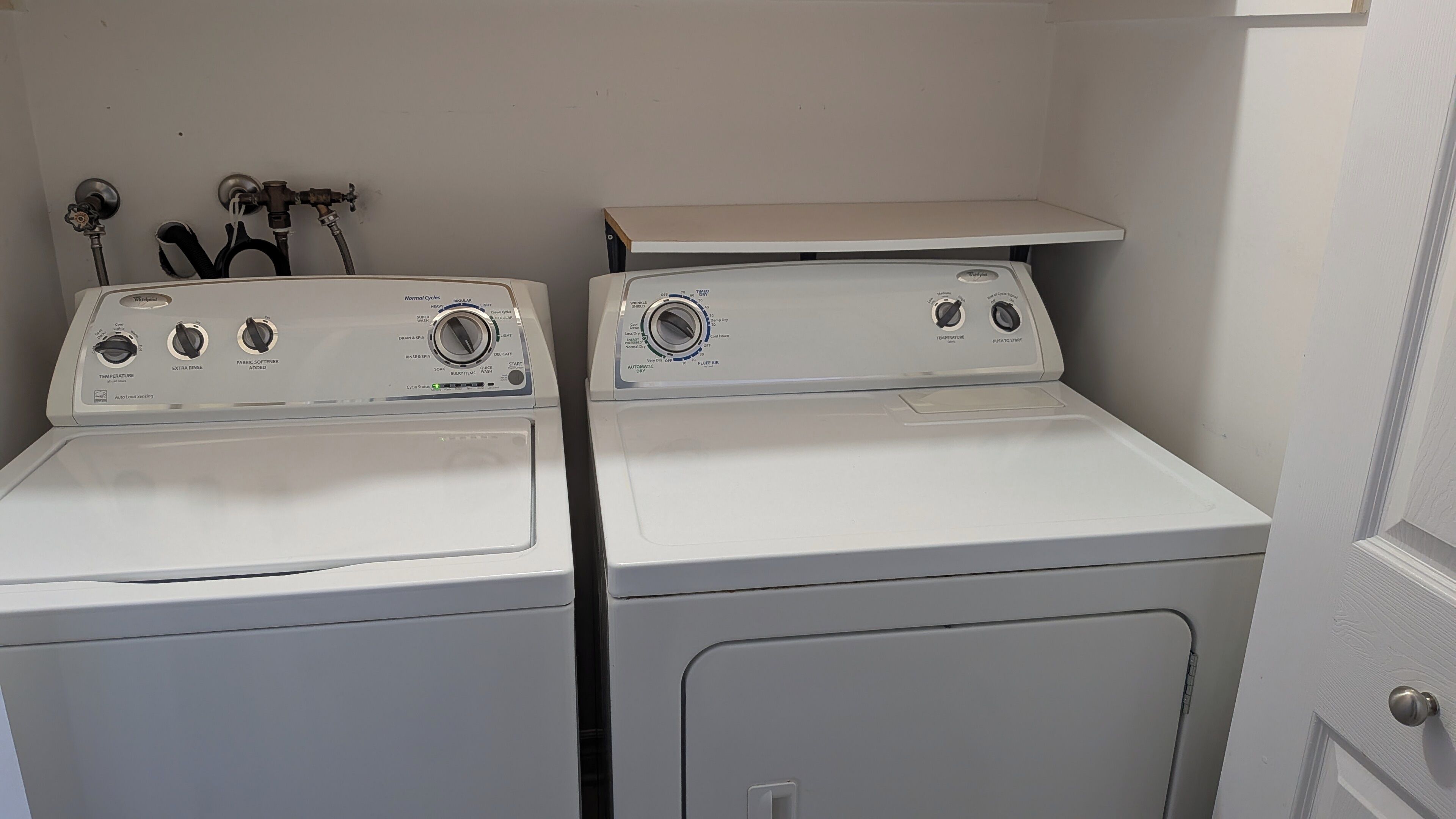 Un cuarto de lavandería con dos lavadoras de carga frontal apiladas.