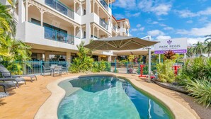 A hotel with a swimming pool, outdoor seating, and a sign indicating it is a Park Regis hotel. - Townsville Apartment Near Stadium & CBD (South Townsville)