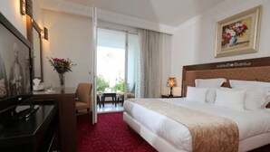 Habitación de hotel con cama, escritorio, silla, televisión y vistas al exterior.