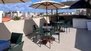 Un patio al aire libre con mesas y sillas, sombrillas y vistas a edificios al fondo.