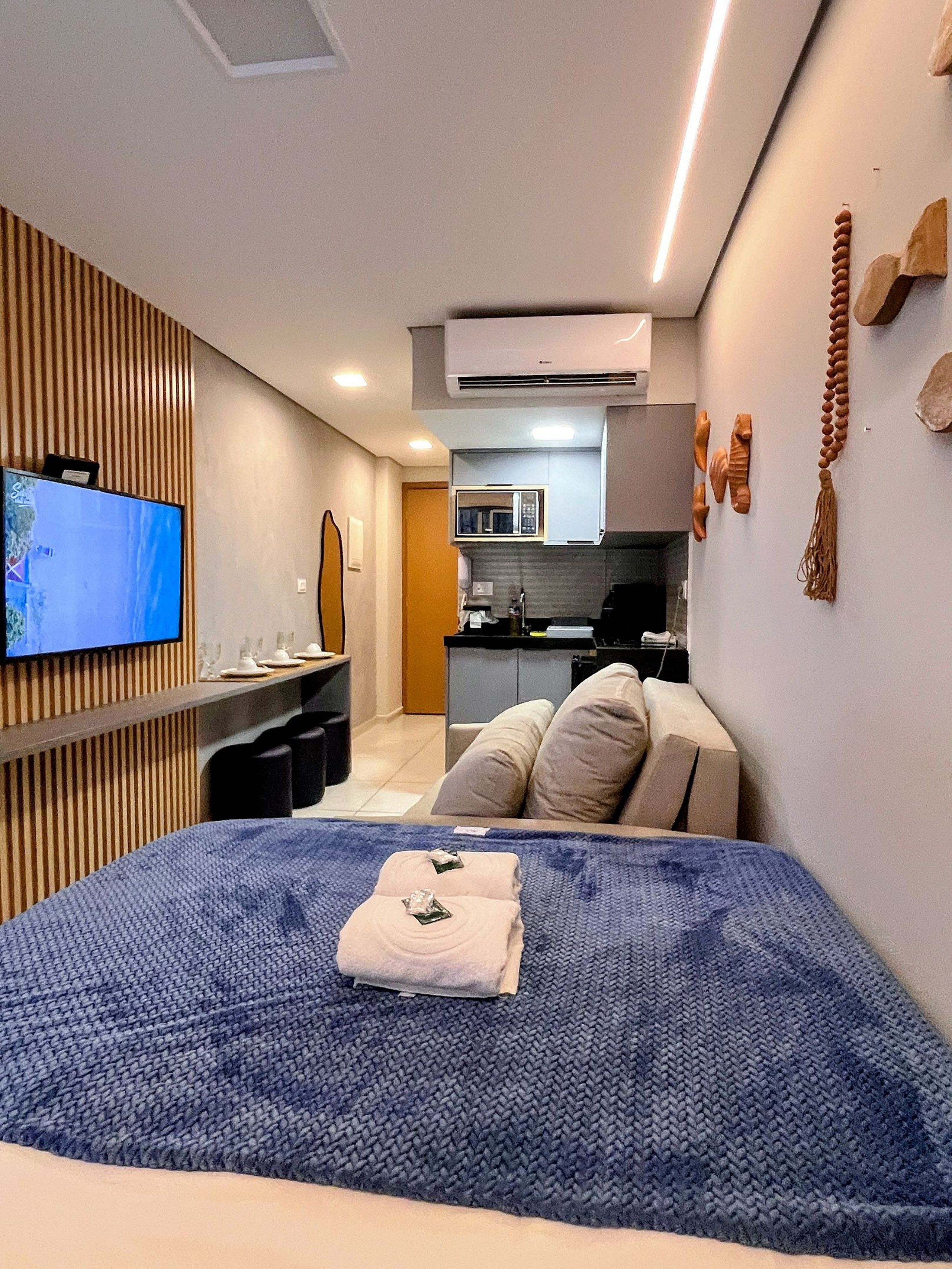 Ein Hotelzimmer mit Bett, Fernseher, Küchenzeile und Badezimmer.