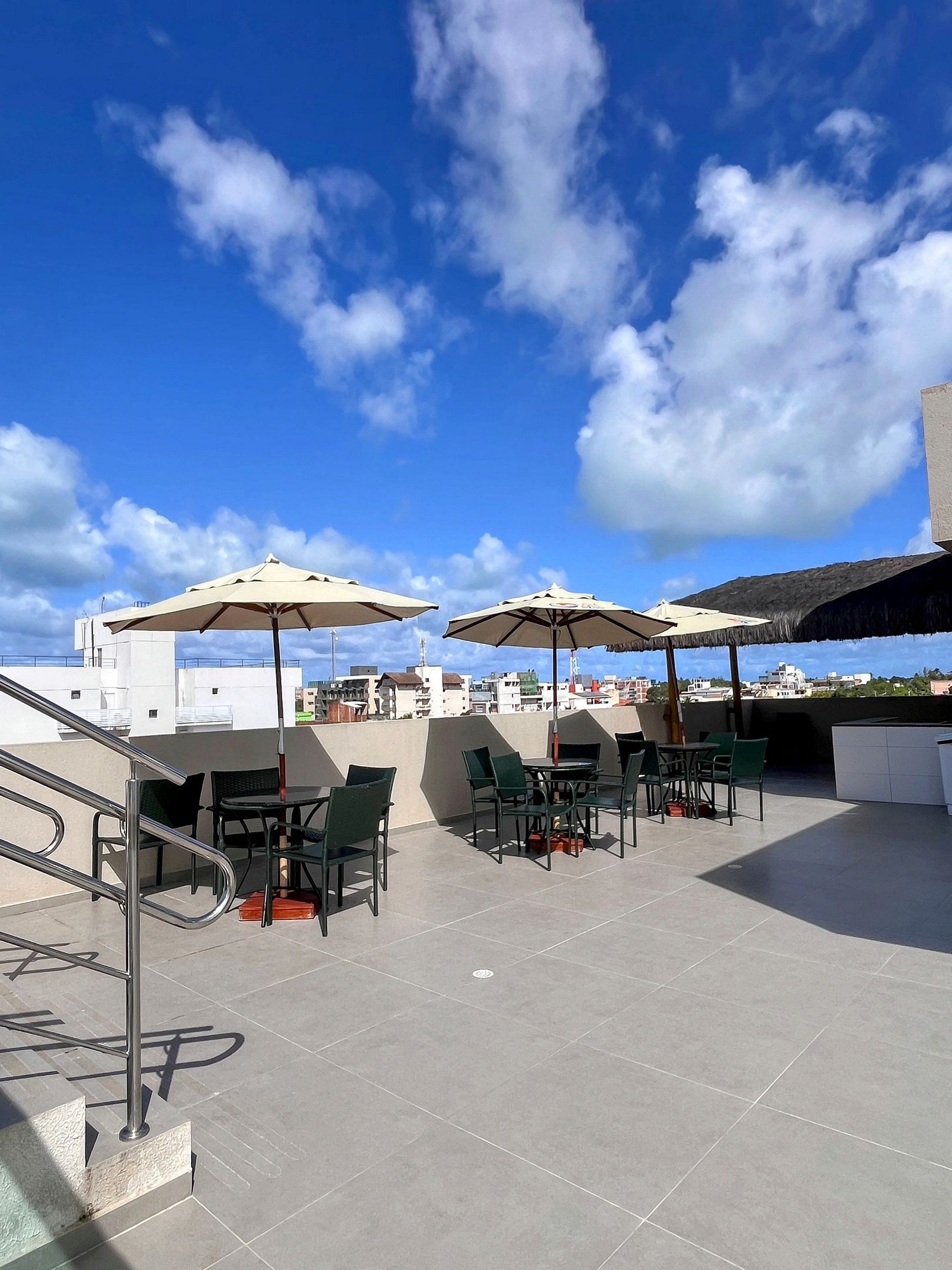 Une terrasse extérieure dotée de nombreuses tables et chaises, de parasols et offrant une vue sur le paysage urbain.