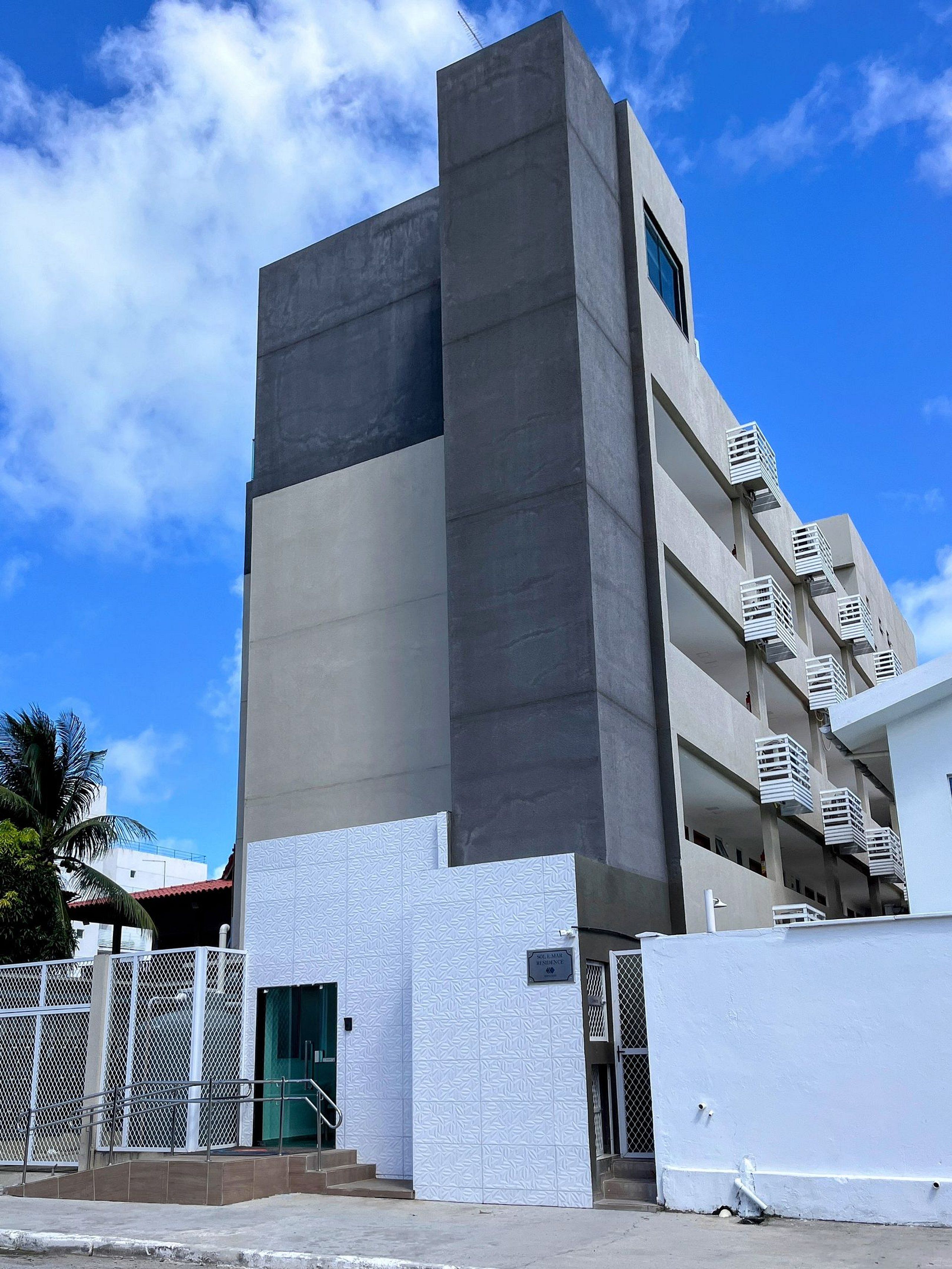 A modern building with a prominent vertical section and multiple balconies.