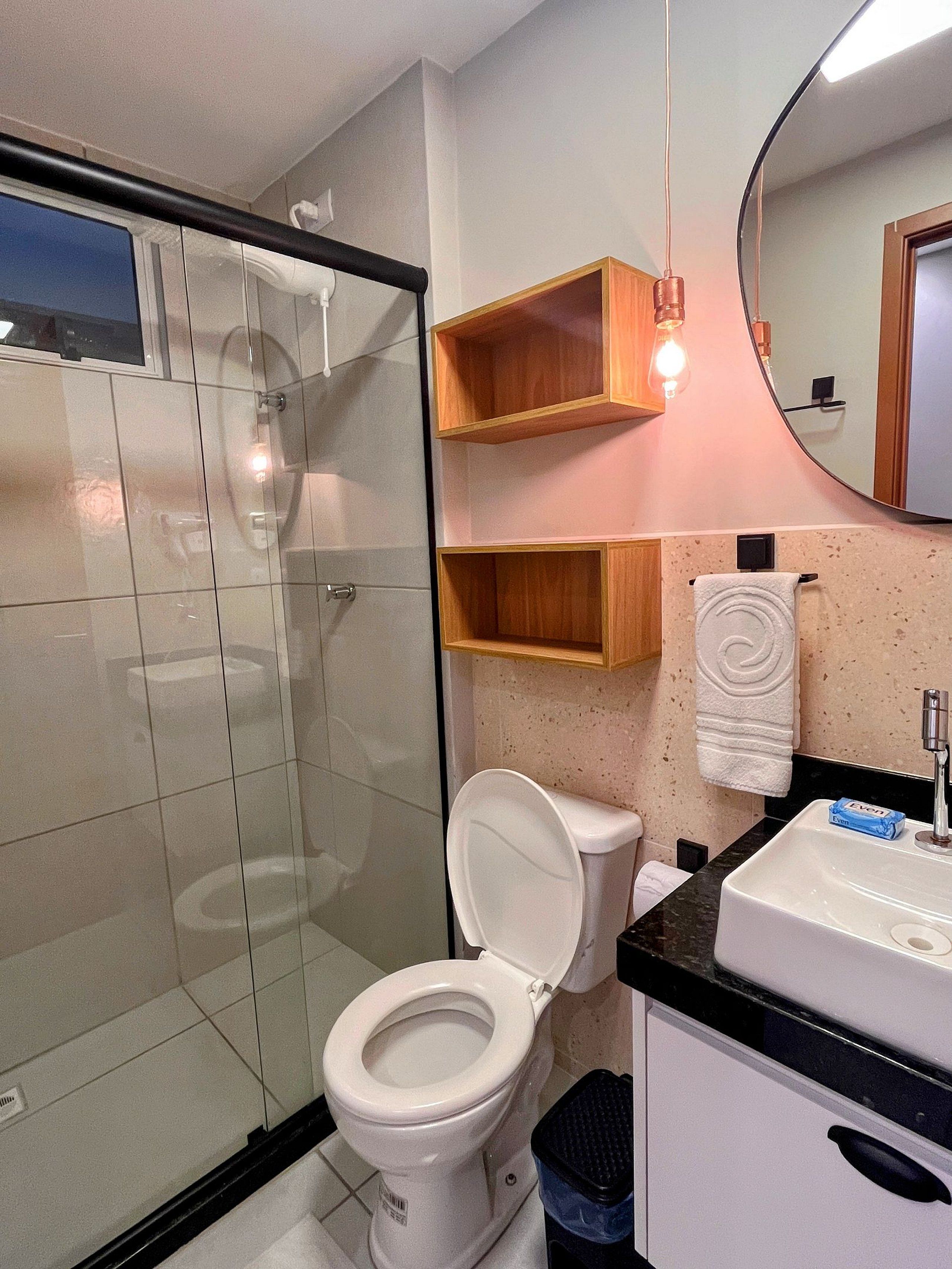 A bathroom with a toilet, a sink, a mirror, and a shower area.