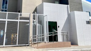 Un edificio moderno con fachada geométrica, acceso mediante portón y cielo despejado.