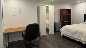 Una camera da letto con un letto, una scrivania, una sedia, un armadio e una mensola.