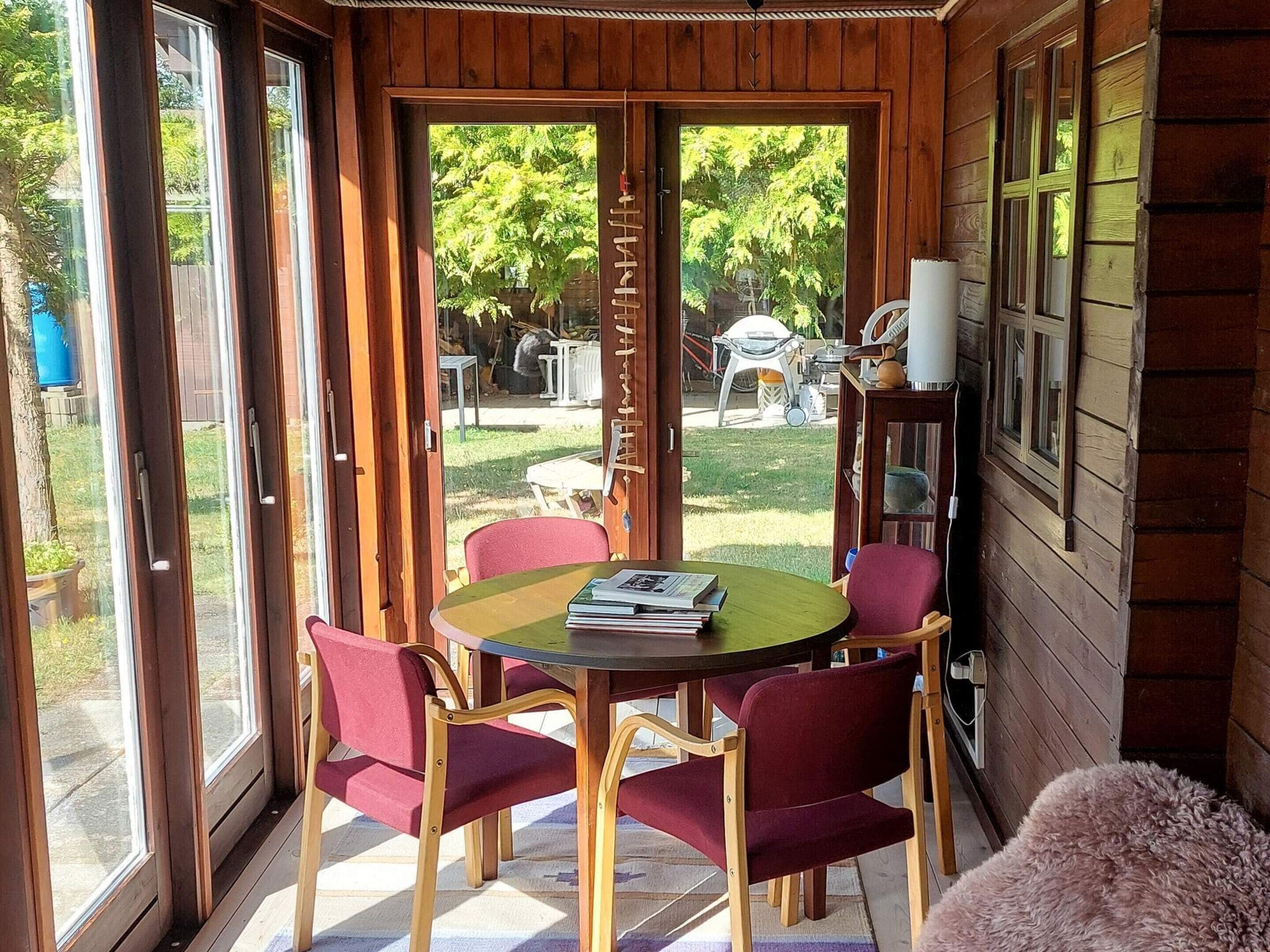Una habitación con detalles de madera, una mesa redonda con sillas y vistas al exterior.