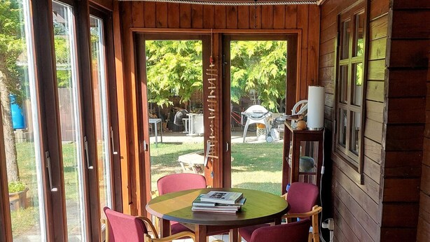 A room with a wooden interior, a round table with chairs, and a view of the outdoors. - 6 Person Holiday Home in Brovst (Brovst)