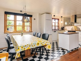 Una cocina con una isla central, una mesa de comedor con sillas y piso a cuadros.