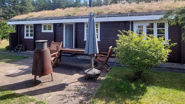 Uma cabana com um espaço de varanda, área de estar ao ar livre e um pequeno jardim.
