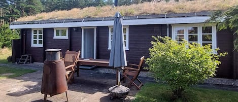 A cabin with a patio area, outdoor seating, and a small garden.