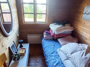A small, cozy room with a bed, a desk with a lamp, and a window with a view of greenery. - 6 Person Holiday Home in Brovst (Brovst)