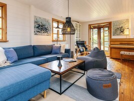 A living room with a blue sofa, a wooden coffee table, a black pendant light, and a piano.