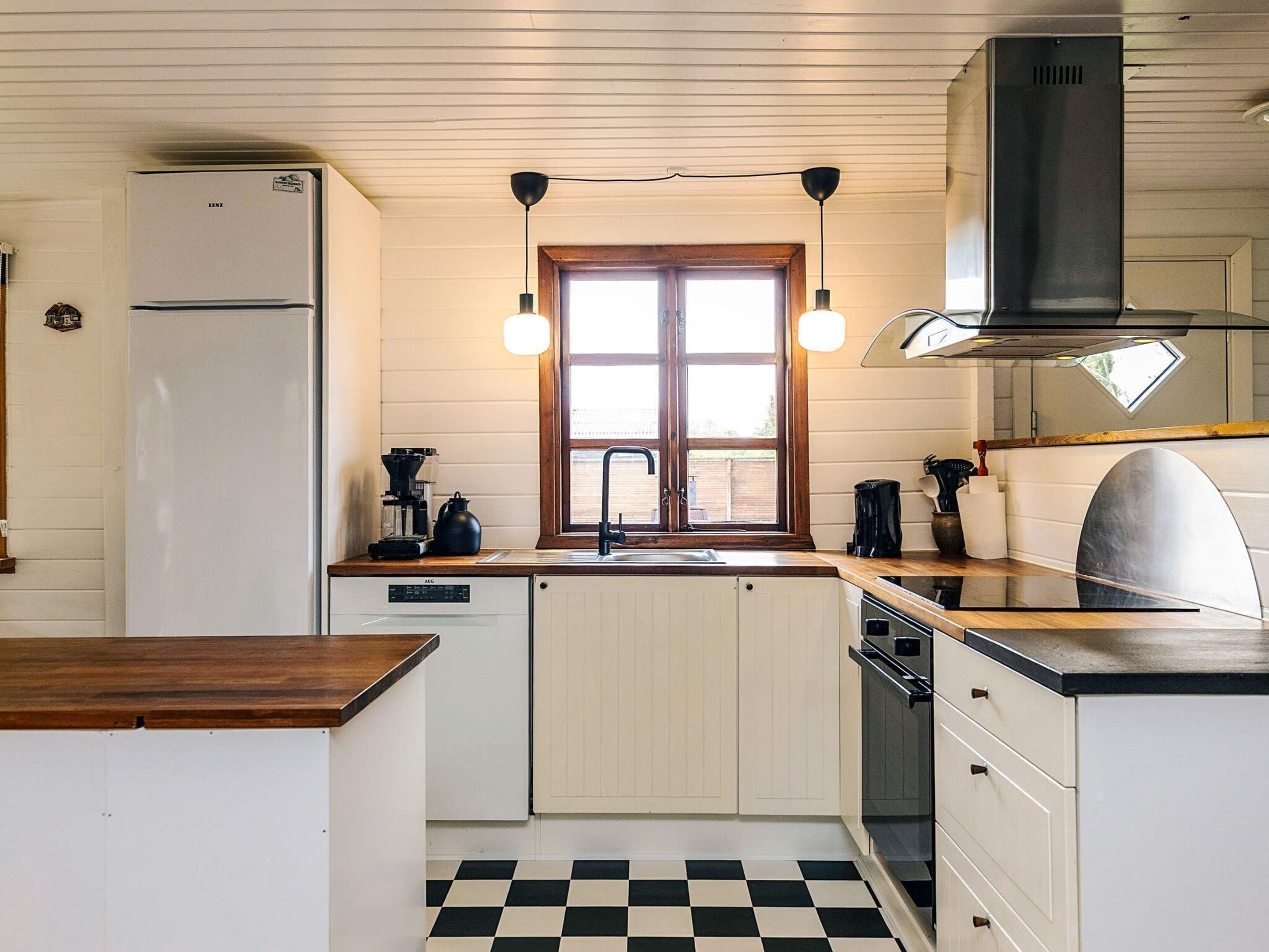 A compact kitchen with a refrigerator, a coffee maker, a sink, and a stove.