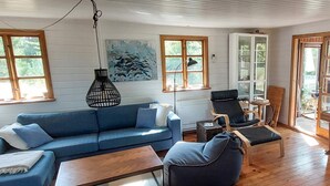 A room with a blue sofa, a wooden coffee table, a blue armchair, and a floor lamp. - 6 Person Holiday Home in Brovst (Brovst)