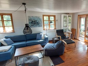 Ein Zimmer mit einem blauen Sofa, einem Holztisch, einem blauen Sessel und einer Stehlampe.