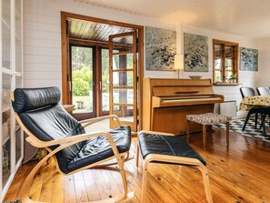 A room with a piano, two rocking chairs, a dining table with chairs, and a view through a glass door. - 6 Person Holiday Home in Brovst (Brovst)