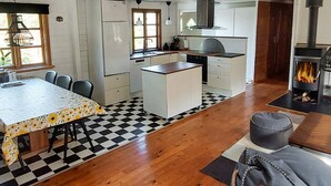 A compact kitchen with a central island, a dining table with chairs, and a built-in wood stove. - 6 Person Holiday Home in Brovst (Brovst)