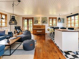 A spacious living area with a piano, a sofa, a dining table, and a kitchen area with a counter.