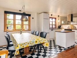 A dining area with a table covered in a sunflower tablecloth, surrounded by chairs.