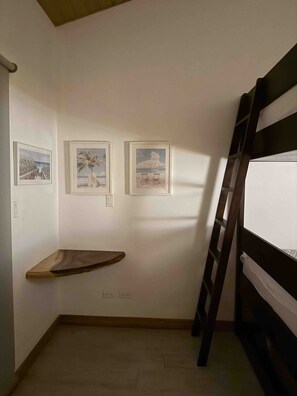 Ein Zimmer mit einem Etagenbett, einer Holzablage und drei gerahmten Bildern an der Wand.