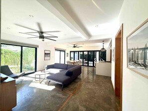 A spacious living area with a large sofa, a dining table, and a ceiling fan. - Quality Home in Perfect Location Close to Beach & Restaurants (Sámara)