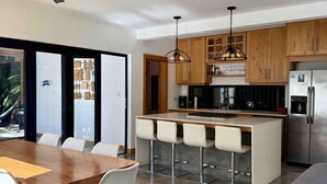 Een moderne keuken met houten kastjes, een roestvrijstalen koelkast en een bargedeelte met krukken.