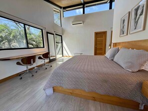 A bedroom with a large bed, a desk, and a chair. There are windows and a door. - Quality Home in Perfect Location Close to Beach & Restaurants (Sámara)